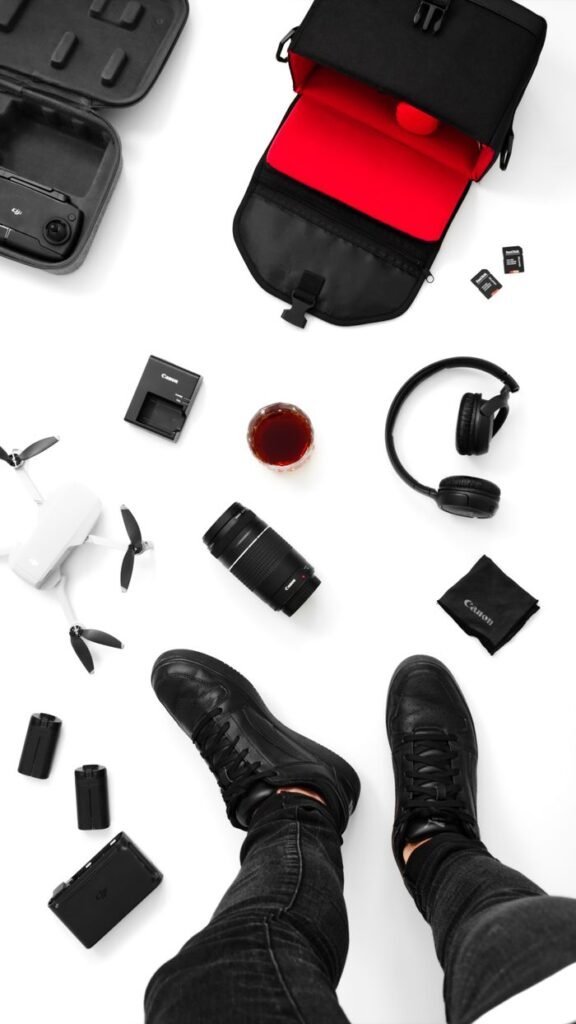 Top view of black boots surrounded by essential photography equipment and gadgets.