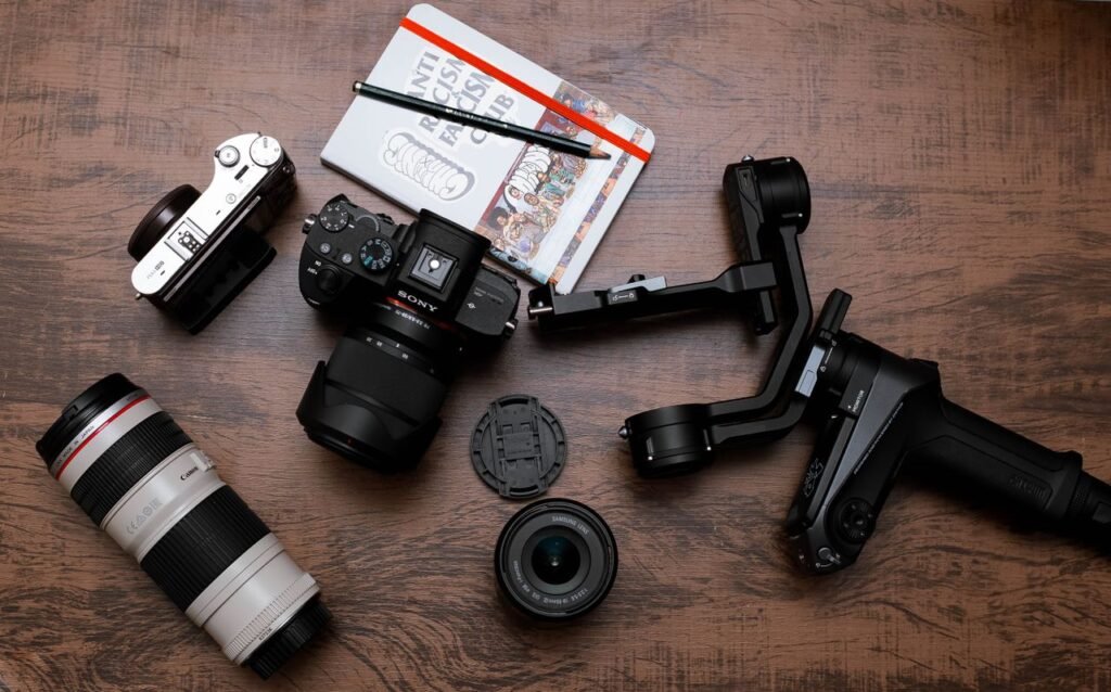 A flat lay of essential photography tools including cameras, lenses, and accessories on a wooden table.