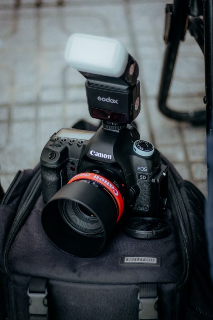 Close-up of a DSLR camera with a flash mounted on a backpack, perfect for outdoor shoots.